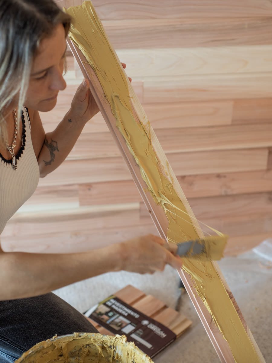 Aplicando adhesivo con espátula sobre una pieza de revestimiento de madera