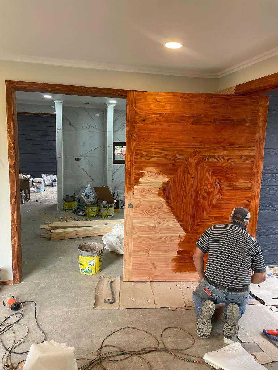 Puerta de Pino Oregón durante la aplicación del acabado, con una mitad ya terminada